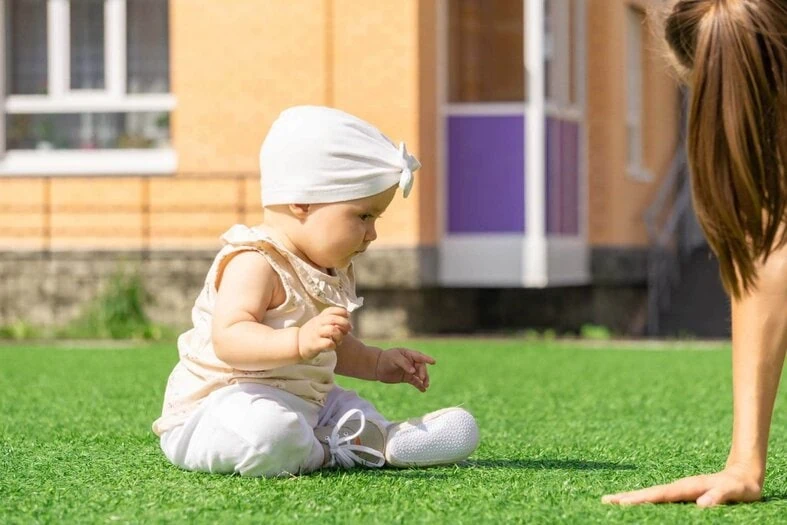 Child enjoying an artificial lawn installed by Gloriously Green Landscaping